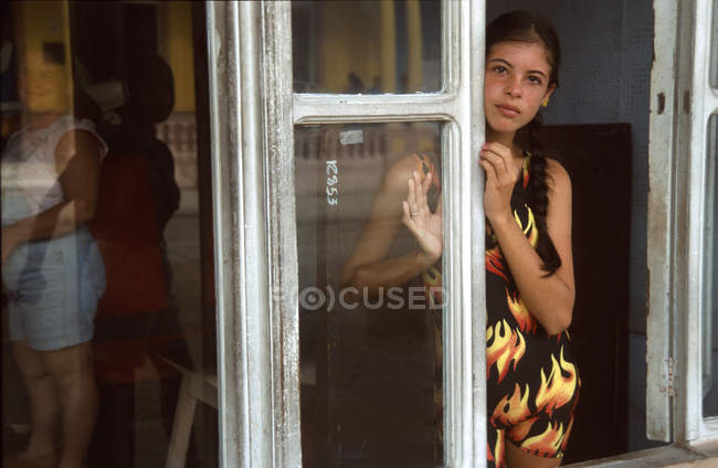 Mujer joven de pie junto a la ventana - foto de stock