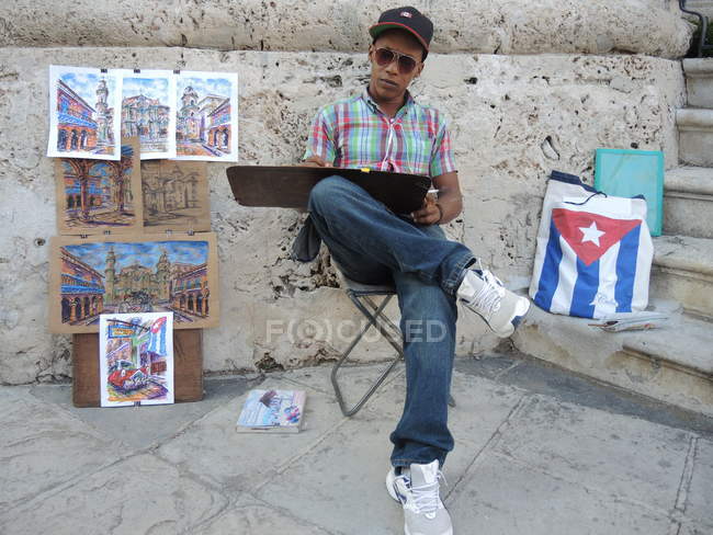 Street artist sitting on chair and drawing — Stock Photo