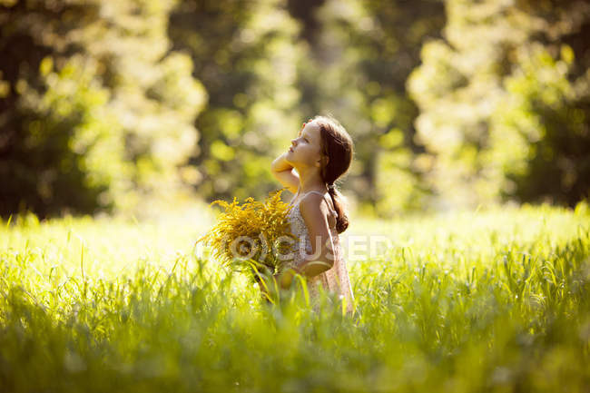Маленька дівчинка стоїть з букетом жовтих квітів — стокове фото