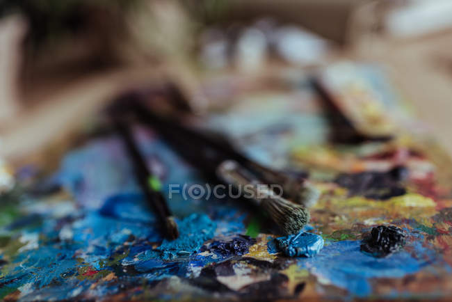 Palette of artist with paint brushes — Stock Photo