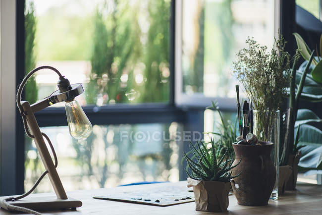 Plantas verdes con suministros de arte en la mesa - foto de stock