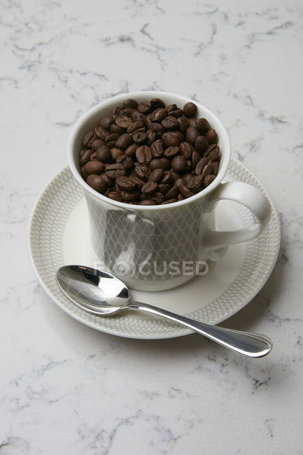 Кофейные зерна в чашке кофе — стоковое фото