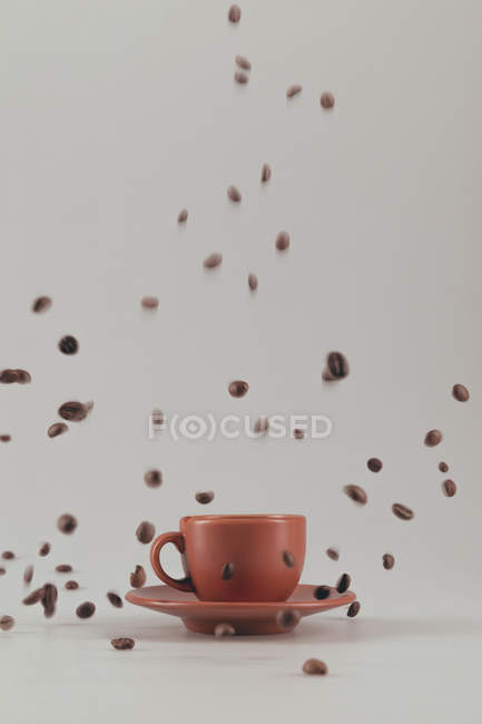 Kaffeetasse mit fallenden Kaffeekörnern — Stockfoto