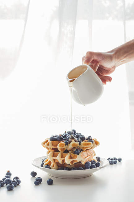 Woman pouring honey on tasty waffles — Stock Photo