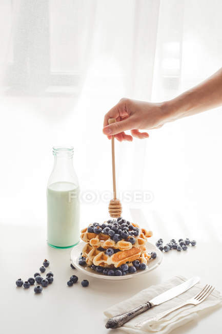 Frau gießt Honig auf leckere Waffeln — Stockfoto