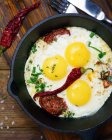 Three fried eggs with peppers and herbs — Stock Photo