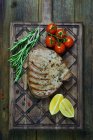 Bistecca di pesce con pomodori, limoni e rosmarino — Foto stock