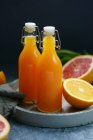 Bottles with juice and oranges on tray — Stock Photo