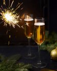 Closeup view of two wine glasses with burning sparkler and fir branches — Stock Photo