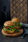 Closeup view of two burgers with sunflower seeds on wooden cutting board — Stock Photo