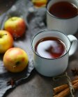 Closeup view of metal cups of tea with apples, cinnamon sticks and anise stars — Stock Photo