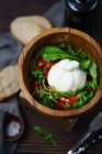 Vue rapprochée de la salade verte aux tomates et au fromage dans un bol en bois — Photo de stock