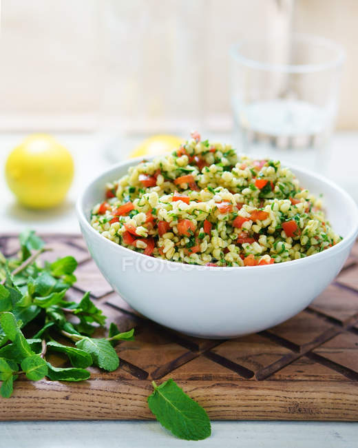 Bowl of bulgur with tomatoes and spinach — Stock Photo