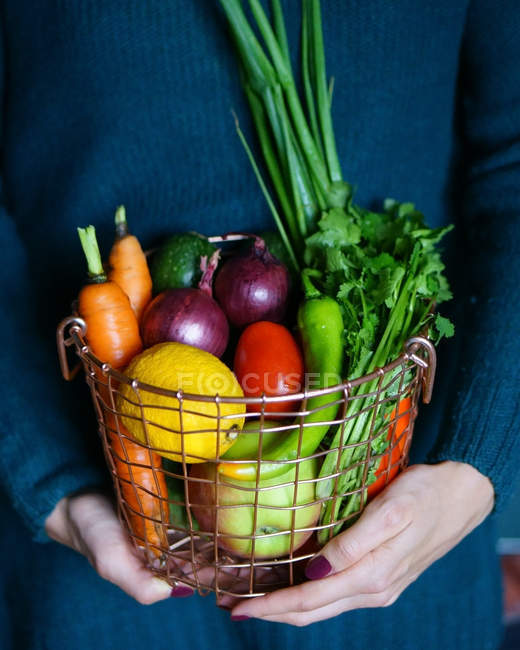 Жінка тримає кошик з овочами та фруктами — стокове фото