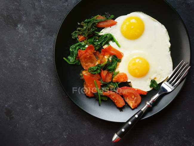 Two fried eggs with roasted tomatoes — Stock Photo