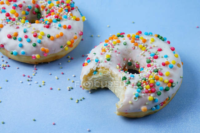 Two doughnuts with icing on blue surface — Stock Photo