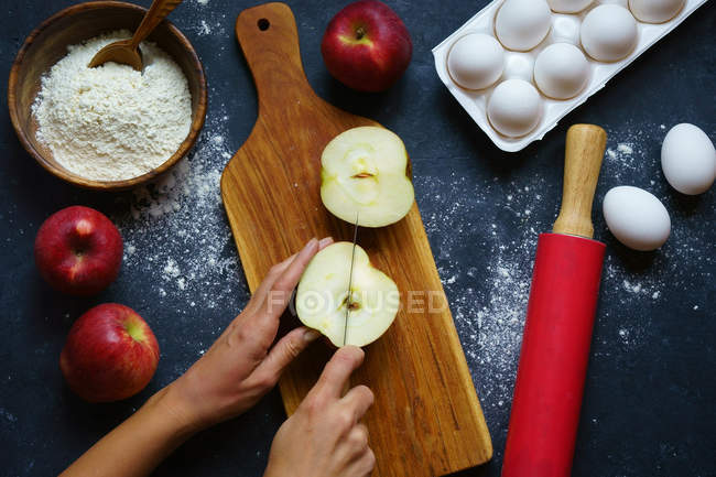 Руки рубають яблуко на дошці — стокове фото