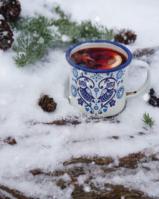 Vista de cerca de la taza de metal de té caliente con rodajas de limón y estrellas de anís en la nieve - foto de stock