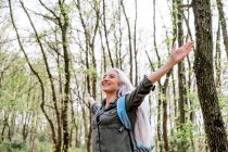 Зрелая женщина с распростертыми объятиями в лесу — стоковое фото