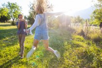 Woman jumping in field being photographed by boyfriend — Stock Photo