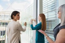 Businesswomen brainstorming ideas on glass window — Stock Photo