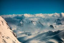 Clouds on snow capped mountain peaks — Stock Photo
