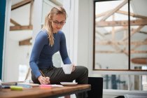 Female designer writing notes — Stock Photo