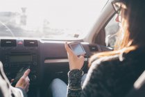 Woman looking at sat nav in front seat of car — Stock Photo