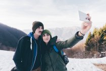 Pareja de senderismo tomando selfie en montañas nevadas - foto de stock