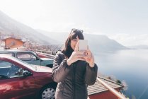 Mulher tomando selfie smartphone à beira do lago — Fotografia de Stock