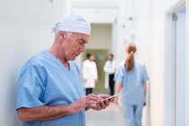 Врач в больнице смотрит на мобильный телефон — стоковое фото