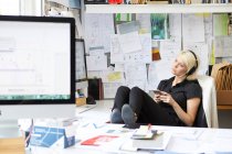 Diseñadora femenina con los pies en el escritorio - foto de stock