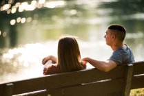 Paar sitzt auf Bank neben Fluss — Stockfoto