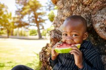 Мальчик ест арбуз в парке — стоковое фото