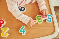 Baby girl playing with toy numerals — Stock Photo