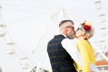 Casal beijando na frente da roda gigante — Fotografia de Stock