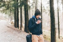 Мужчина турист смотрит на смартфон в лесу — стоковое фото