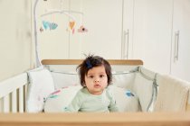 Baby girl staring from crib — Stock Photo