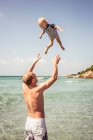 Père jetant un jeune fils dans l'air — Photo de stock