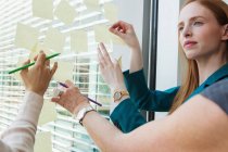Geschäftsfrauen beim Brainstorming von Ideen für Glasfenster — Stockfoto