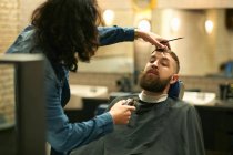 Hairdresser trimming customers beard — Stock Photo