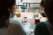 Mujeres jóvenes sentadas en la cafetería - foto de stock