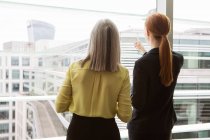 Geschäftsfrauen stehen im Büro am Fenster — Stockfoto