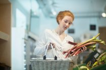 Woman in shop holding shopping basket — Stock Photo