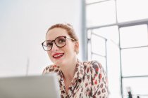 Woman in office wearing reading glasses — Stock Photo