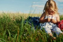 Female toddler sitting in field — Stock Photo