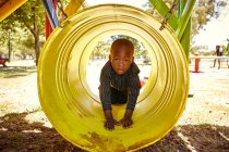 Niño en túnel de arrastre en el patio de recreo - foto de stock