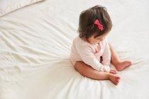 Bébé fille assis sur le lit — Photo de stock