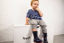 Männliches Kleinkind sitzt auf Spielzeugkiste — Stockfoto