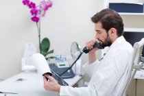 Médico en el escritorio haciendo una llamada telefónica - foto de stock
